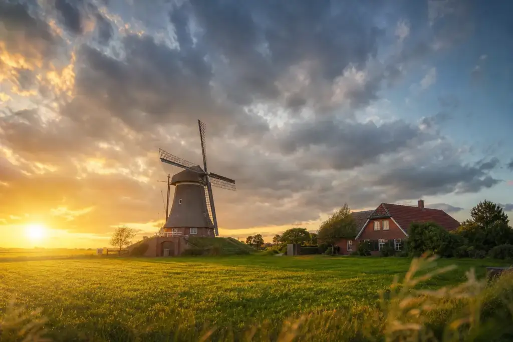 Ostfriesische Landschaft mit Windmühle und Klinkerhof im Abendlicht